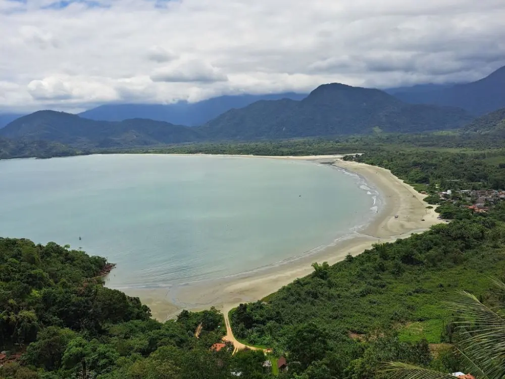uma praia com um corpo de água e montanhas ao fundo